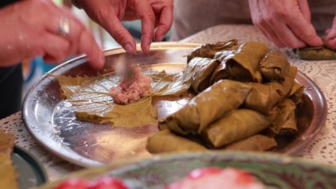 People cook dolma food. Grape leaves stuffed with minced meat.	