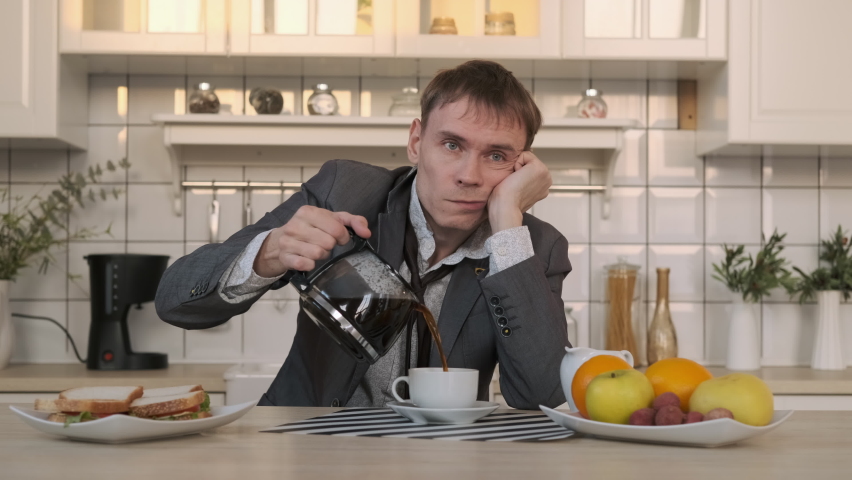 Tired Man Pouring Coffee Early in the Morning, Having Breakfast after Sleepless Night. Coffee Spills over the Rim of Cup. Business, Lifestyle, Overworking Concept Royalty-Free Stock Footage #1086318317