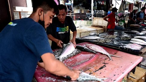 jakarta, indonesia on jan 31, 2022: defocused. two asian man fish trader is cleaning the scales and skin of milkfish to sell before Chinese New Year in petak 9 market, selective focus