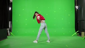 A young woman dancing on a green screen background. Attractive girl making content for social media. Modern blogger creating a master class. Chroma key
