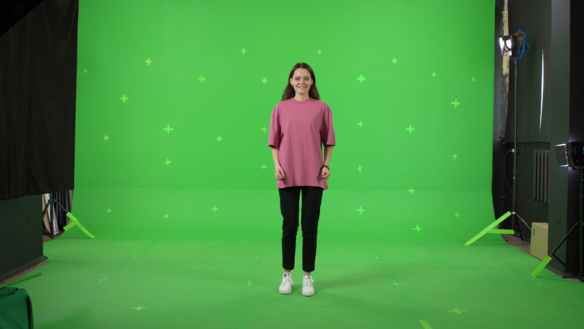 Young woman dancing on a green screen background. Girl makes a gesture with her hands as if swipping the page to the side . Chroma key Royalty-Free Stock Footage #1086319715