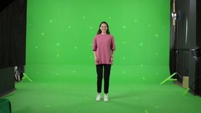 Young woman dancing on a green screen background. Girl makes a gesture with her hands as if swipping the page to the side . Chroma key
