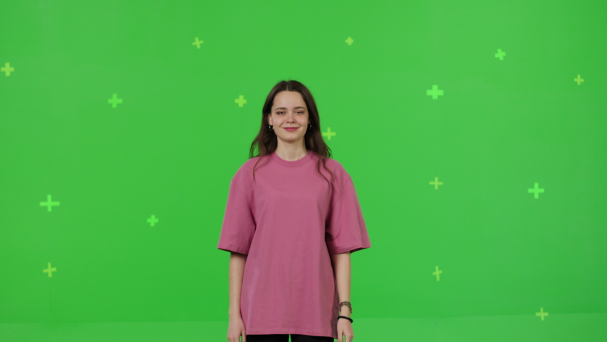 Close-up of young woman dancing on a green screen background. Girl makes a gesture with her hands as if swipping the page to the side . Chroma key Royalty-Free Stock Footage #1086319763
