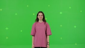 Close-up of young woman dancing on a green screen background. Girl makes a gesture with her hands as if swipping the page to the side . Chroma key