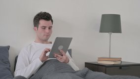 Man doing Video Call on Tablet while Sitting in Bed
