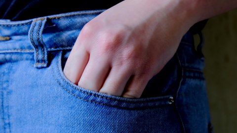 Hand takes a condom out of jeans pocket