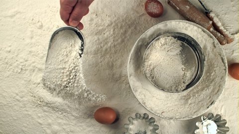 Super slow motion human hand pours flour on the table of the scoop. On a white background.Filmed on a high-speed camera at 1000 fps. Top view. High quality FullHD footage