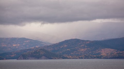 the movement of clouds with rain and snow over the autumn mountains on the shore of Lake Baikal