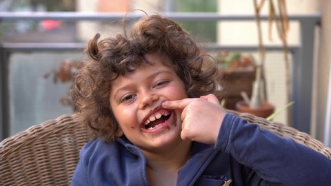 7 year old children boy smiles looking at  camera and shows milk teeth with a recently fallen tooth ( losing a tooth )   - dental care in childhood, face full of chocolate 