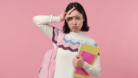 Girl teen student of Asian ethnicity in shirt hold backpack books do crazy expression squint eyes isolated plain pastel light pink background studio portrait. Education in high school college concept