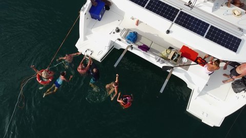 Phuket, Thailand, 21, December, 2021:
A group of tourists swims in the sea near a sailing catamaran during a sea cruise in the tropics, top view