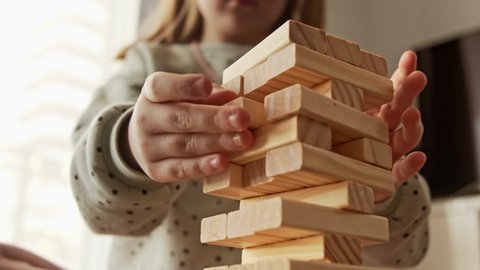 Little child plays a board game, kid builds from wooden bricks blocks. Children's educational games concept.