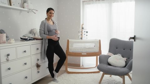 Caucasian woman in advanced pregnancy standing in the baby's room next to the crib. Shot with RED helium camera in 8K.