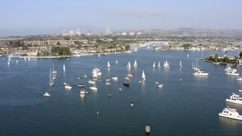 Aerial Reversing High Over Sailboats In A Busy Harbor With A City In The Background - Newport Beach, California
