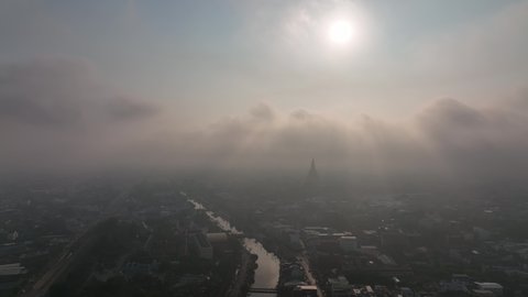 flying above Phra Prathom Chedi city with mist slowly form town over the clouds 4k stock footage