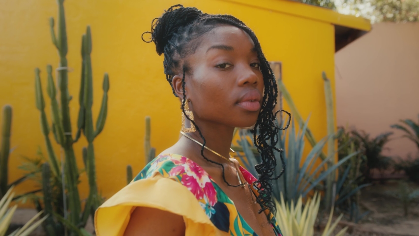 A beautiful black model poses for a photographer. Stylish fashion photo shoot in a cactus garden