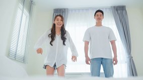 Asian attractive loving couple enjoy dance together in bedroom at home. Young romantic new marriage man and woman recording challenge video virtual clip sing song music after wake up from bed in house