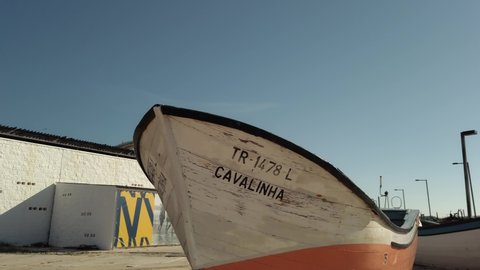 Costa de caparica , Portugal - 01 25 2022: Panning across small wooden fishing boats on sunny Costa de Caparica under blue sky