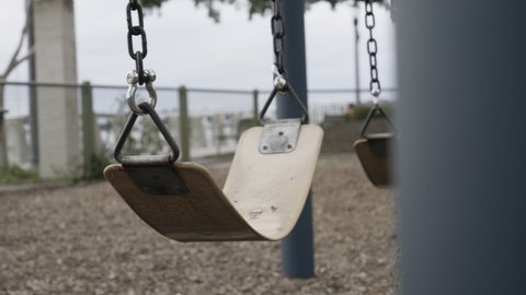 Empty children's playground at the park with swing swinging. 