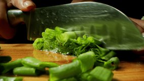 Chopping macro photography of green onions, cooking process, delicious and bright image, sharp knife, cutting green onions, dark background in the background. Close-up video vegetarian, vegan cuisine 
