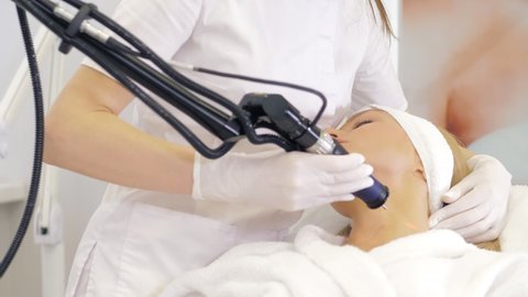 A cosmetologist performs hardware laser hair removal for a patient in an aesthetic medicine clinic.Laser pulses cleanse the skin.Hardware cosmetology.Elimination of pigments.Red Laser.Close-up
