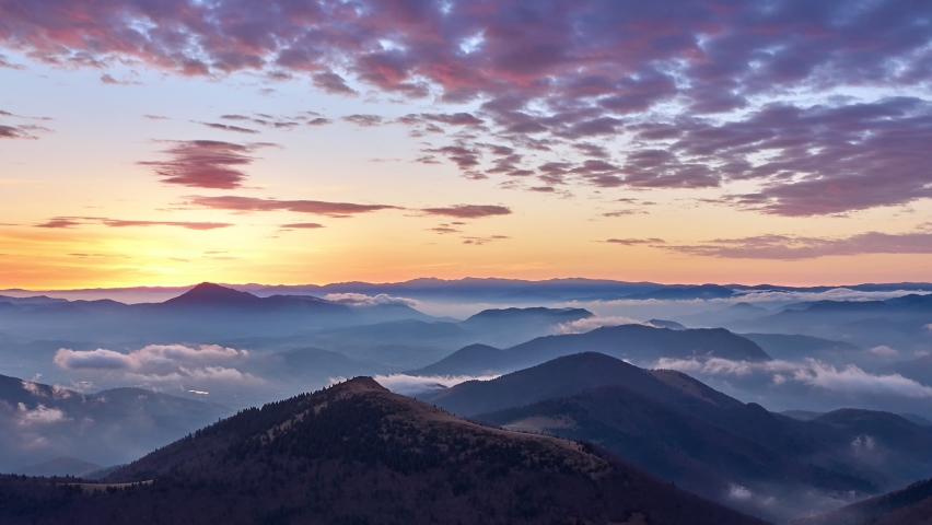 Sunrise in the mountain landscape, fog spills over hills. Colored clouds in red orange,Epic morning