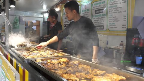 MANCHESTER, ENGLAND, UNITED KINGDOM - CIRCA SEPTEMBER, 2021: Takeaway or takeout team of young chefs cooking steaming jerk chicken and other Jamaican food.