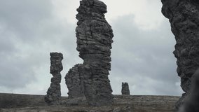 Group of friends go hiking in the mountains. Clip. People walk between stone pillars. Hiking in cloudy weather in the mountains