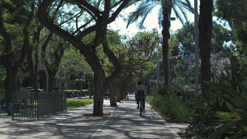 A cyclist on the sidewalk of a park in the center of Tel Aviv on Rabin Square. Rear view.