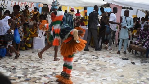 Abidjan, December 12, 2021: A gouro mask dancing to the sound of drummers surrounded by spectators outside. 
