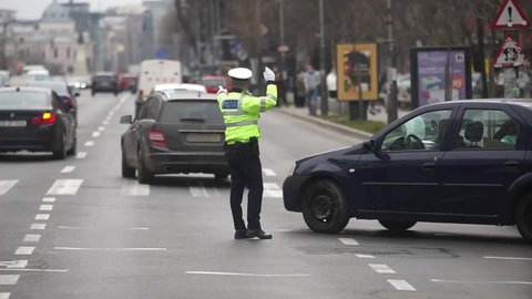Bucharest, Romania - April 28, 2021: A policeman directs cars traffic at an intersection in Bucharest.