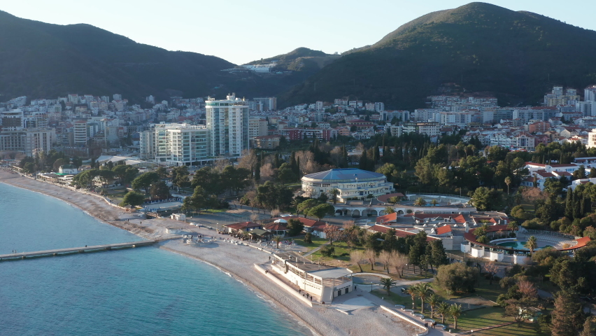 Budva Montenegro: empty sand beach in winter season. European town on the coast of the Mediterranean sea. City between the shore and hills and mountains. Adriatic coastline - landscape and cityscape.  Royalty-Free Stock Footage #1086386666