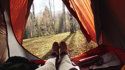 Women's Legs In Yellow Hiking Boots Lie In A Orange Tent. From The Tent View Of Mountains And Forest. Traveling Alone In The Mountains. The Traveler Is Resting, Admiring The Mountains After Climbing Stock Video
