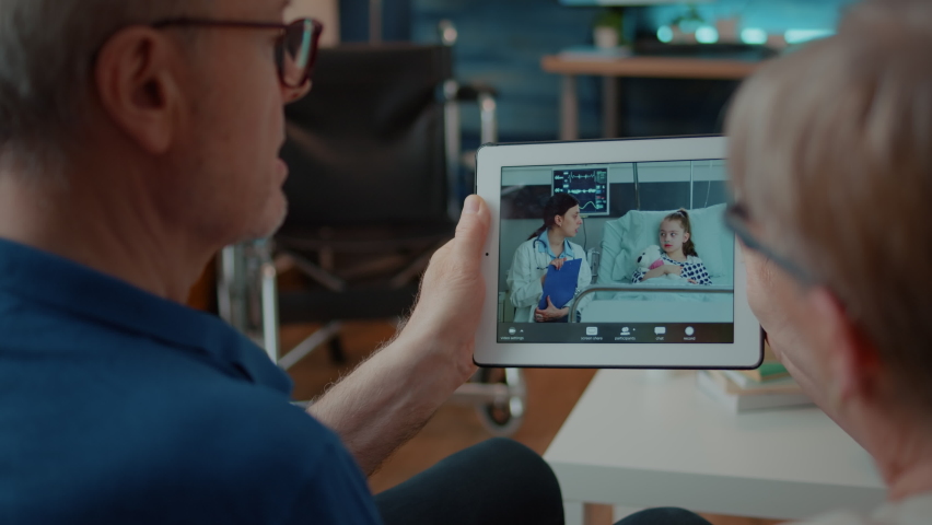 Retired couple holding digital tablet to talk on video call with doctor and child. Old people using device wih teleconference to chat with specialist and niece in hospital. Online conference Royalty-Free Stock Footage #1086389132