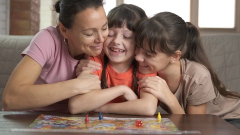 Children and adult with board game. Children with her good looking mother play board game in the room.