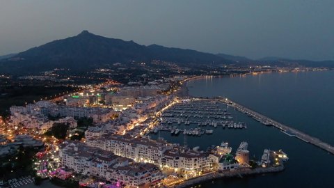 Aerial drone panoramic view of Puerto Banus Marbella marina luxury port at dusk	