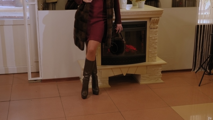 A woman with long dark hair tries on a fur coat in a clothing store. Portrait of a model girl in a fur store.