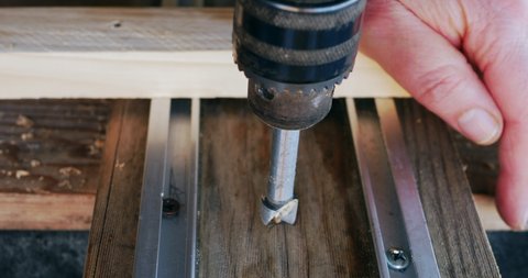 Close-up of router wood fixed with clamps on a wooden surface with which a hobbyist drills a circular hole in a piece of wood