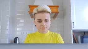 Beautiful tom boy woman with short dyed hair working on laptop at home on lockdown. Freelancer female doing distant work on notebook computer in kitchen in 4k stock video