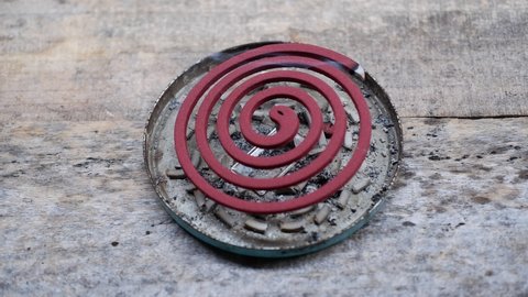 Red mosquito coil repellent with the rest of the burning ashes on a wooden background