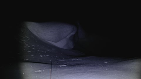 Snow dunes in the mountains at night. Increased risk of avalanches. The snow sparkles from the beams of a headlamp. Night serenity and danger. Hiding a threat. Rescue operation