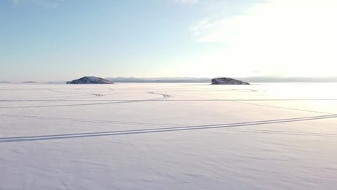 Winter landscape of snow-covered Lake Baikal with rocks and hills on a sunny frosty day. Shooting from a drone