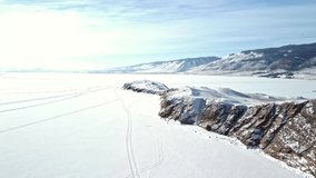 Winter landscape of snow-covered Lake Baikal with rocks and hills on a sunny frosty day. Shooting from a drone