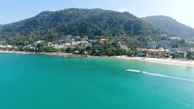Speedboat drags banana boat on sea. 4k aerial view Phuket,Thailand sea, famous beach tourist destination no people. Cityscape seaside mountains background. 