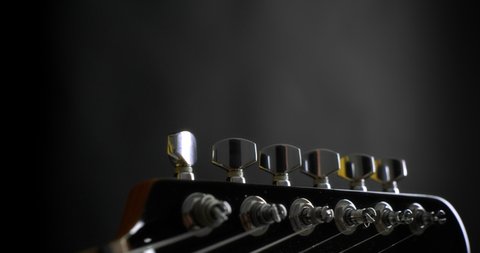 Close-up of the guitarist turns the knobs on the neck of an electric guitar.Black background. High-quality 4K video. Shot with RED camera. Slow motion.