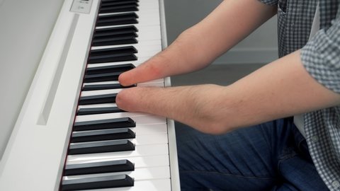 Young man with amputated two hands is playing the piano, closeup hands. Life of guy person musician with physical disability. He's trying to keep playing after the injury.