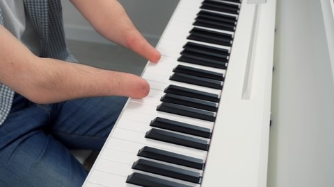 Young man with amputated two hands is playing the piano, closeup hands. Life of guy person musician with physical disability. He's trying to keep playing after the injury.