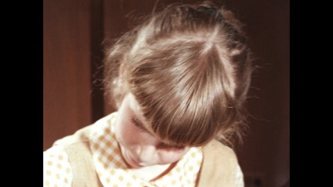 1960s: Close up of girl. Hand with paper. Lollipops on table, hand puts number cards on stands.
