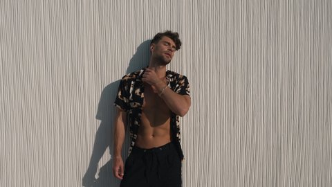 muscular man in a shirt posing against a wall