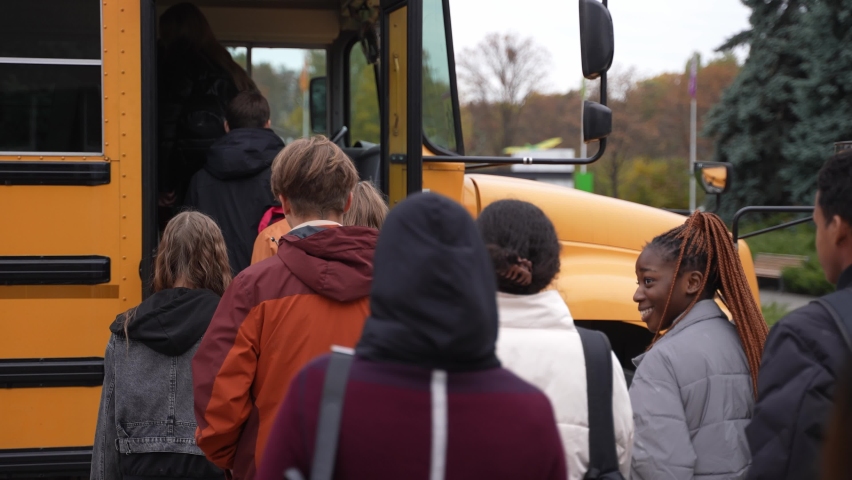 Back view of multi-ethnic high school students getting on yellow school bus after lessons. Group of diverse teenage secondary school pupils boarding school bus at the end of studies Royalty-Free Stock Footage #1086417380